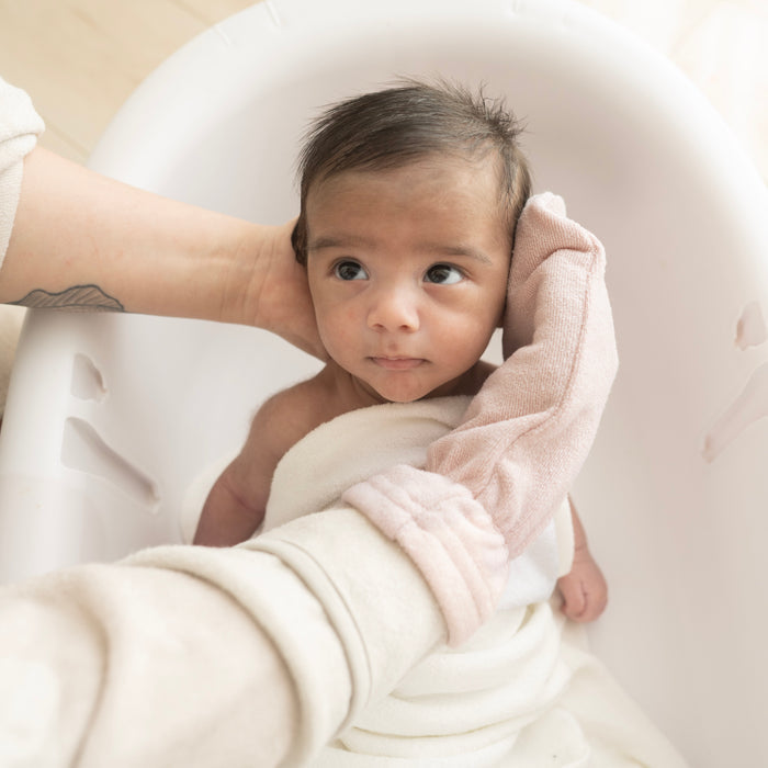 Parent using Blush Pink Terry Bath Mitt for newborn bath