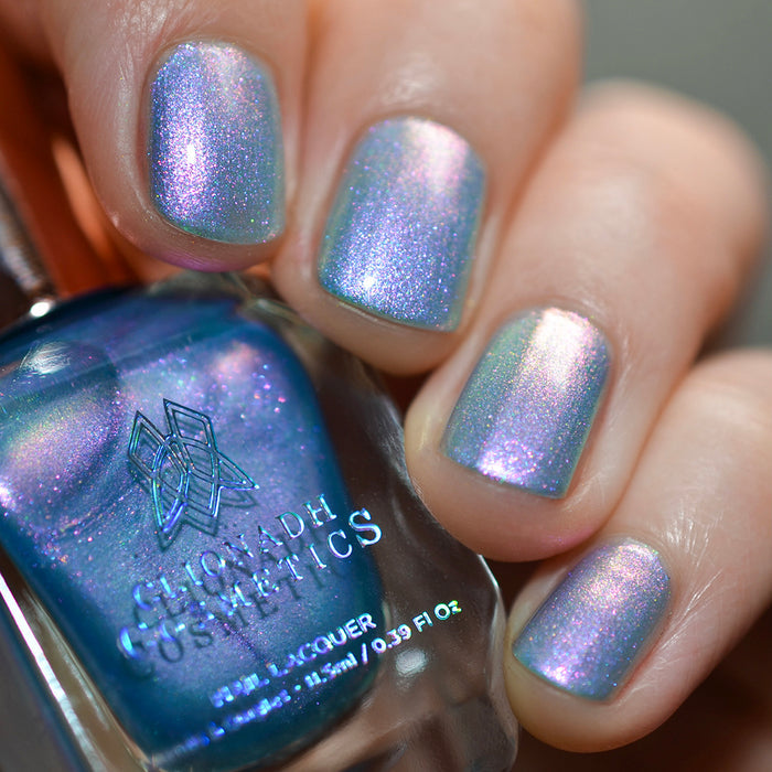 Close-up of nails painted with Tessera Nail Lacquer on fair skin tone. Hand is holding polish bottle.