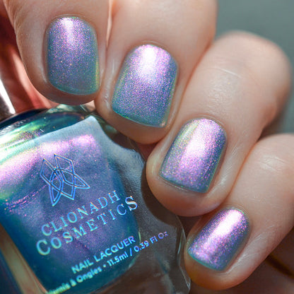 Close-up of nails painted with Tessera Nail Lacquer on fair skin tone. Hand is holding polish bottle.