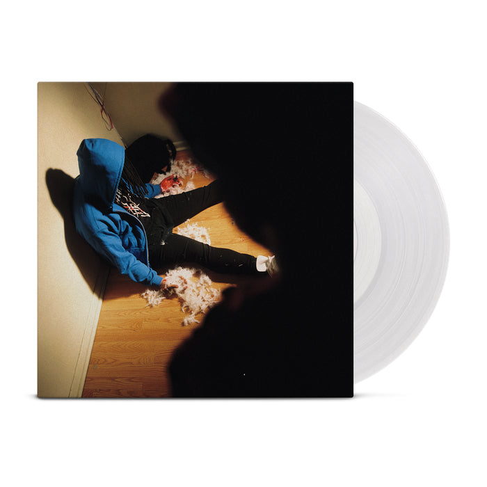 A picture of a man with a blue hoodie and dreads slumped over against a wall with a dark figure over him is on this vinyl jacket. A clear vinyl peeks out of the jacket.