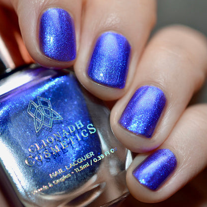 Close-up of nails painted with Tiara Nail Lacquer on fair skin tone. Hand is holding polish bottle.