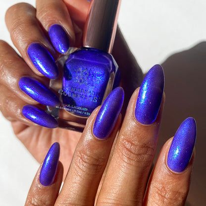 Nails painted with Tiara Nail Lacquer on medium skin tone. Hand is holding polish bottle.