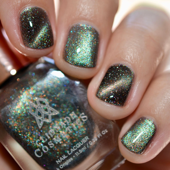 Close-up of nails painted with Tombstone Nail Lacquer on fair skin tone. Hand is holding polish bottle.