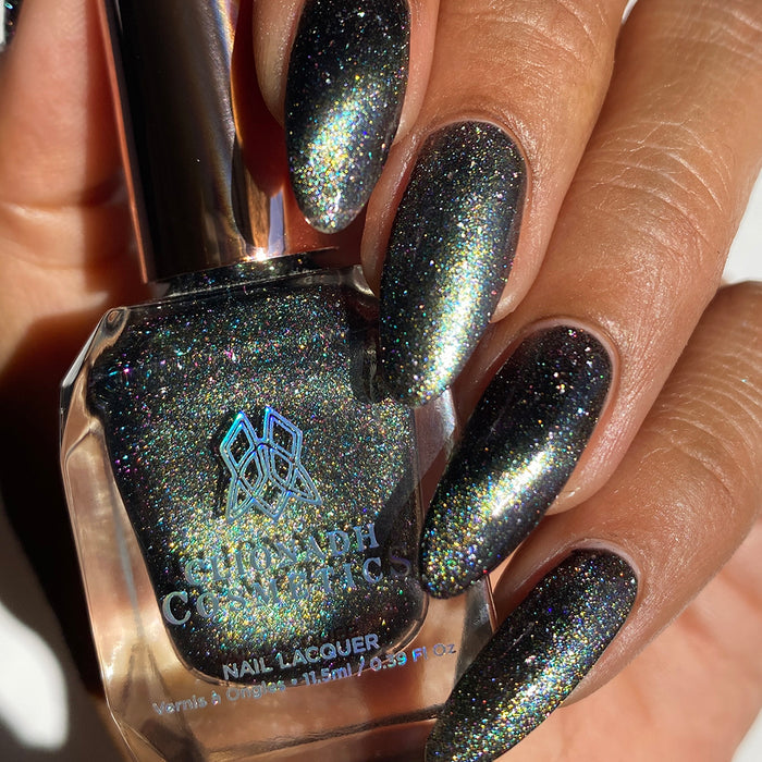 Close-up of nails painted with Tombstone Nail Lacquer on medium skin tone. Hand is holding polish bottle.