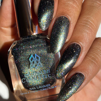 Close-up of nails painted with Tombstone Nail Lacquer on medium skin tone. Hand is holding polish bottle.