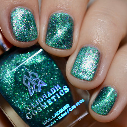 Close-up of nails painted with Turquoise Silk Nail Lacquer on fair skin tone. Hand is holding polish bottle.