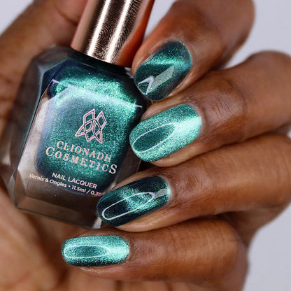 Close-up of nails painted with Turquoise Silk Nail Lacquer on deep skin tone. Hand is holding polish bottle.