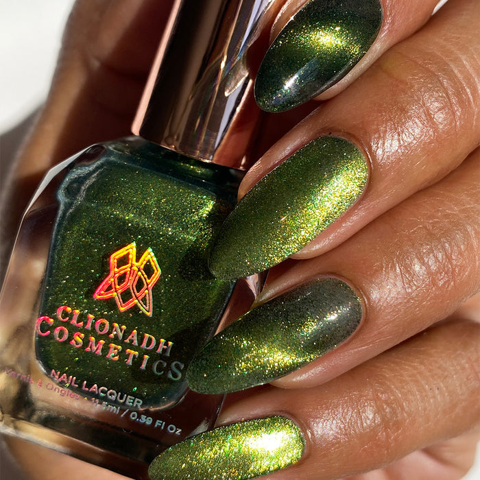 Close-up of nails painted with Velvet Verdigris Nail Lacquer on medium skin tone. Hand is holding polish bottle.