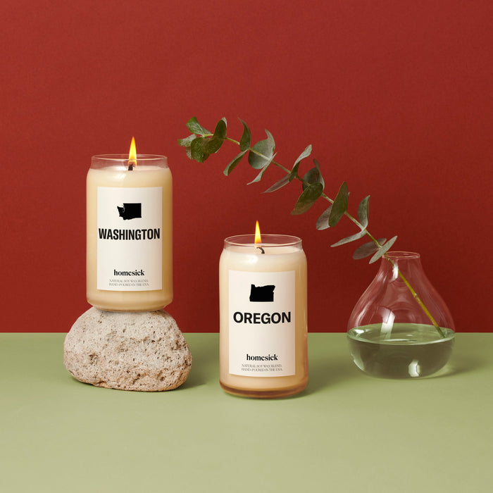 Left to right, the Washington candle balanced on a rock, the oregon candle on the green surface, a glass container with eucalyptus coming out.