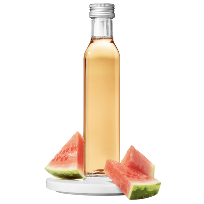 A clear bottle of watermelon vinegar with a silver cap, accompanied by slices of fresh watermelon.