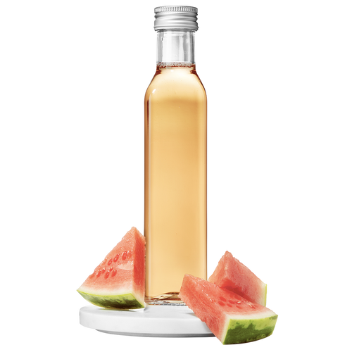 A clear bottle of watermelon vinegar with a silver cap, accompanied by slices of fresh watermelon.