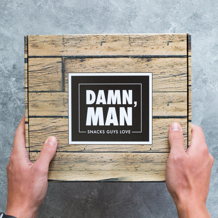 Hands holding Damn, Man gift box with gourmet snacks for men