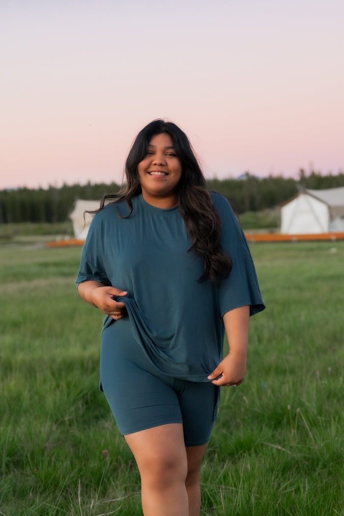 Smiling female model standing in a field wearing the Women’s Biker Short Set in Atlantic