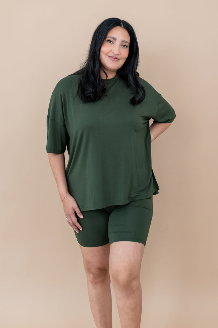 Woman wearing a bamboo biker set in a deep green color on a beige background