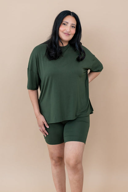 Woman wearing a bamboo biker set in a deep green color on a beige background