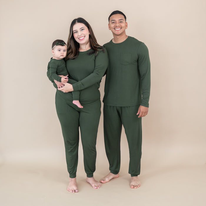 Family of three wearing matching green outfits against a beige background