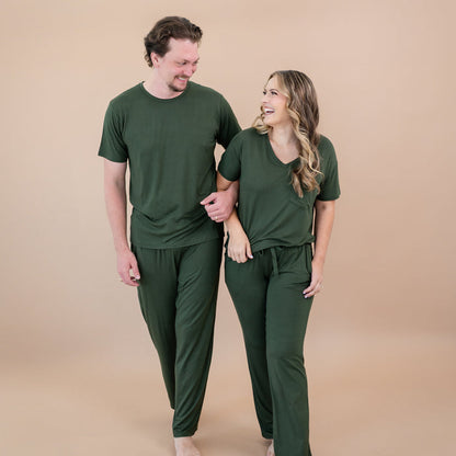 Man and woman wearing matching green bamboo loungewear against a beige background
