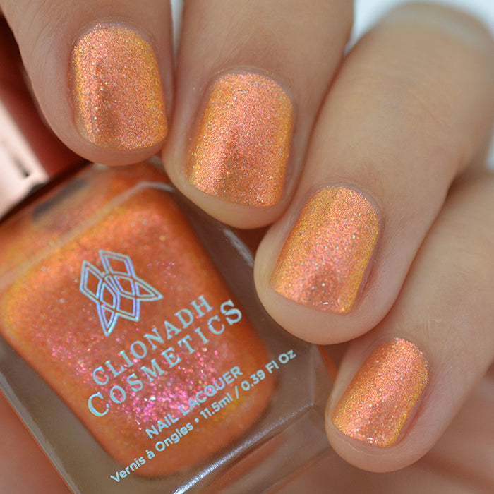 Close-up of nails painted with Yuzu Limonada Nail Lacquer on fair skin tone. Hand is holding polish bottle.